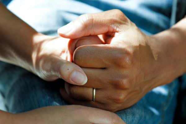 A close-up of a carer holding patient's hand - representing the community care sector
