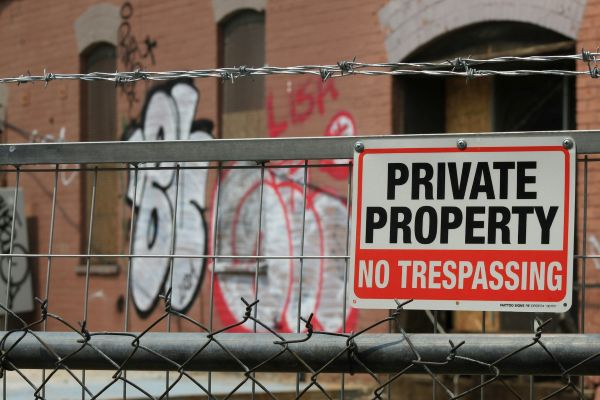 Generic void property image - a fence with "no trespassing" sign and a wall with graffiti in the background